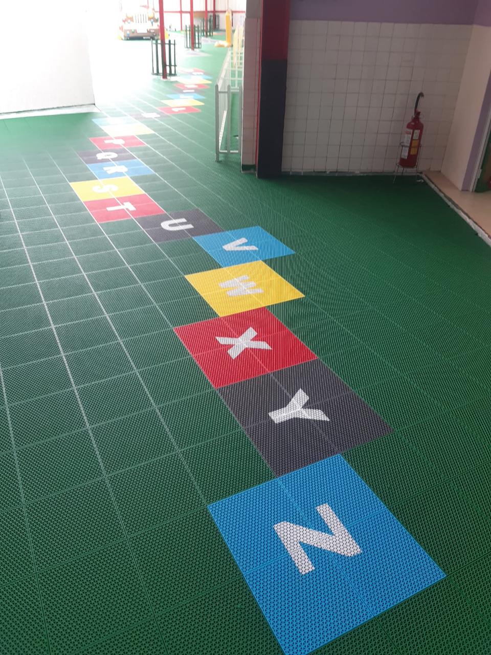 Área interna com piso modular verde e letras coloridas