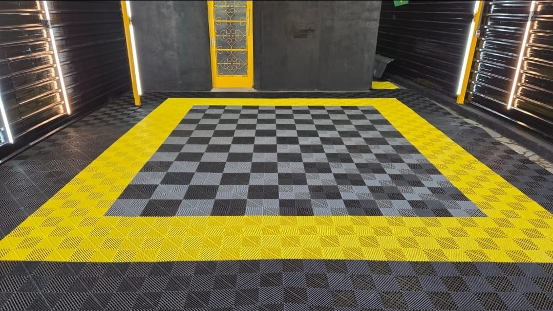 Garagem com piso modular amarelo e preto em padrão xadrez