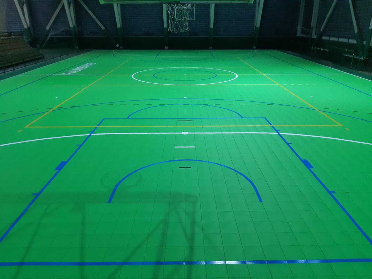 Quadra poliesportiva com piso modular verde e demarcações