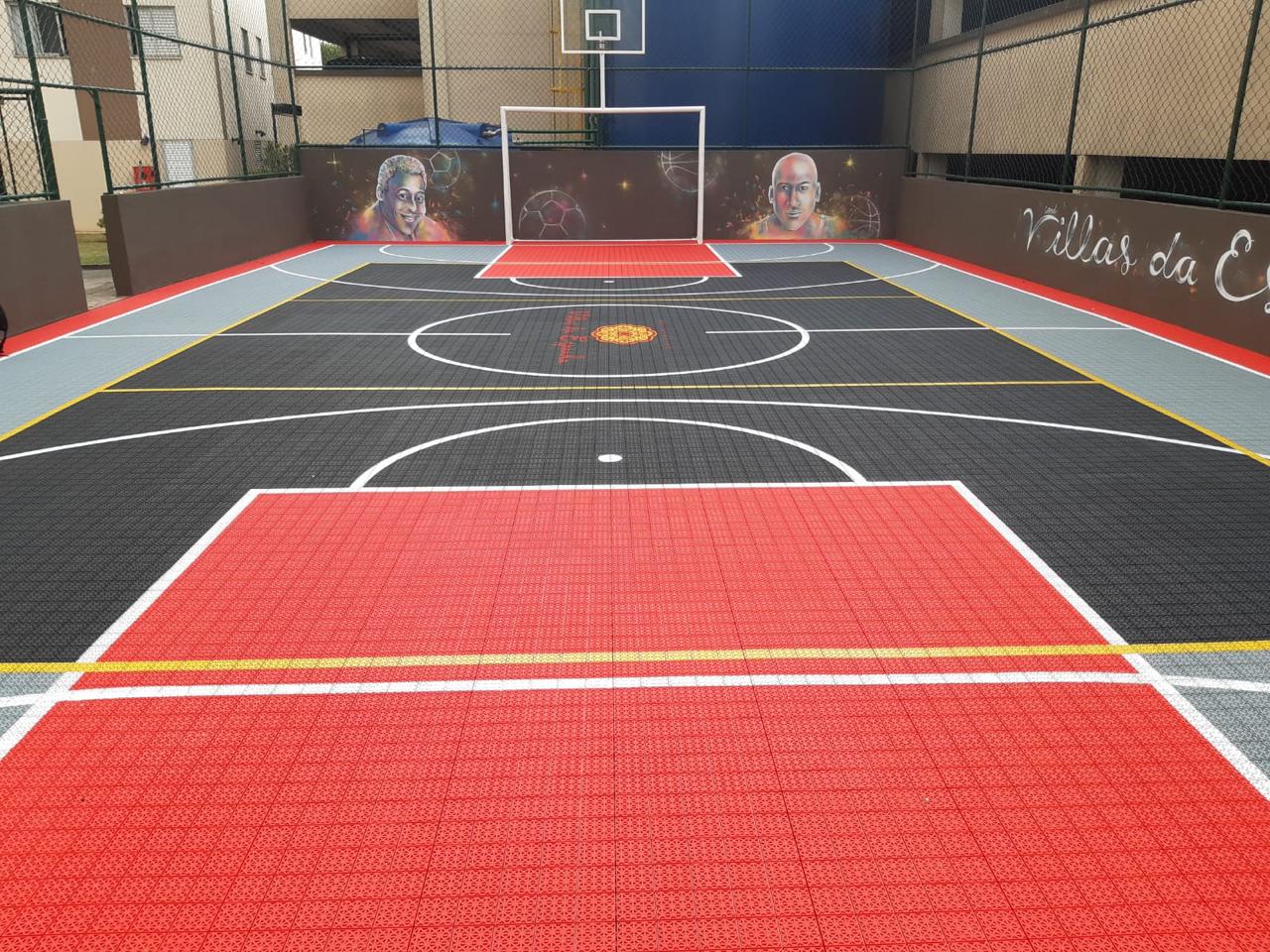 Quadra de condomínio com piso modular preto, vermelho e cinza